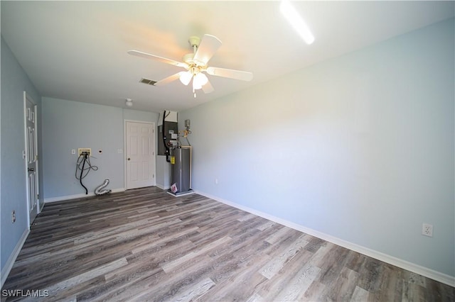 empty room featuring ceiling fan, wood-type flooring, and water heater