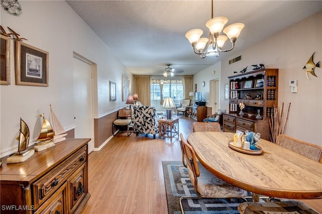 dining room featuring ceiling fan with notable chandelier, a textured ceiling, and light hardwood / wood-style flooring