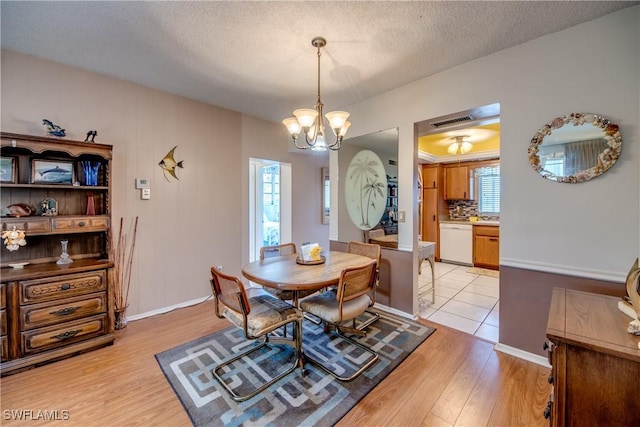 dining room featuring an inviting chandelier, a textured ceiling, and light hardwood / wood-style flooring