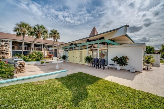 rear view of property featuring a patio area and a lawn