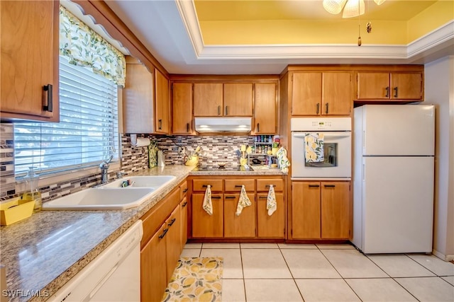 kitchen featuring sink, light tile patterned floors, a tray ceiling, white appliances, and decorative backsplash