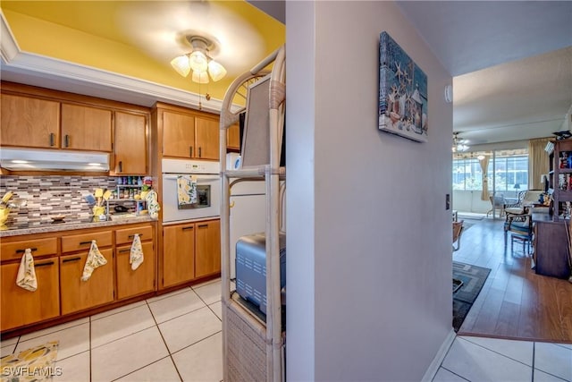 kitchen with tasteful backsplash, black electric cooktop, white oven, and light tile patterned floors