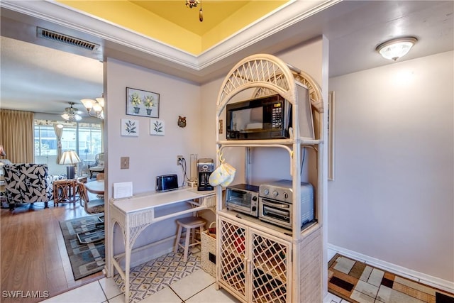 tiled office with ornamental molding and a raised ceiling