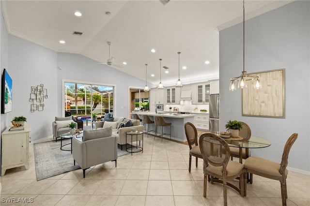 dining room featuring ceiling fan, light tile patterned floors, vaulted ceiling, and ornamental molding