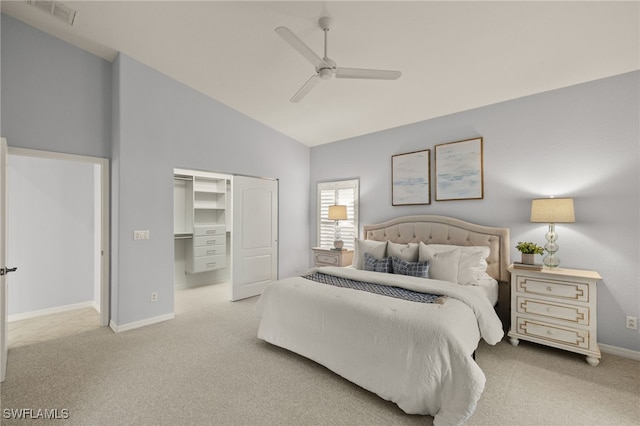 bedroom featuring light carpet, ceiling fan, a walk in closet, and a closet