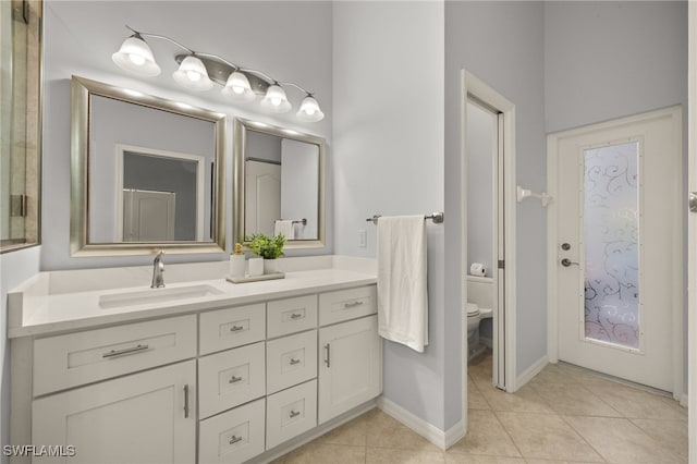 bathroom with toilet, vanity, and tile patterned flooring