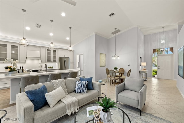 tiled living room featuring sink, ornamental molding, a towering ceiling, and an inviting chandelier