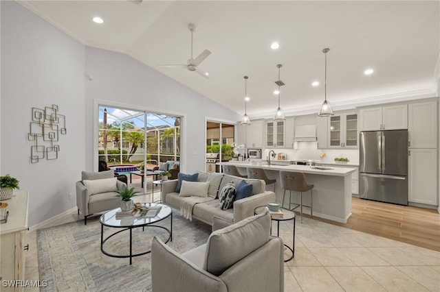 living room with lofted ceiling, sink, ornamental molding, light tile patterned flooring, and ceiling fan