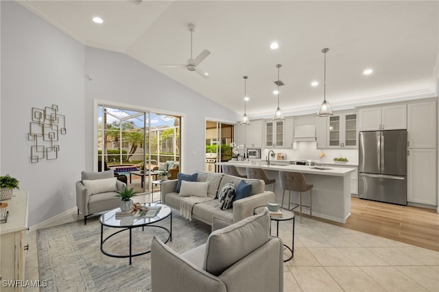 living room featuring ceiling fan, light tile patterned flooring, vaulted ceiling, ornamental molding, and sink