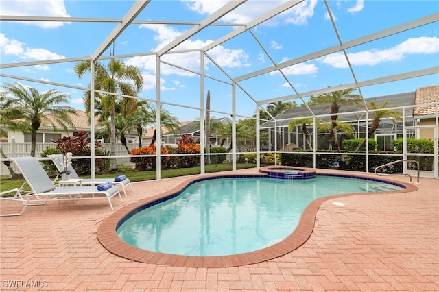 view of pool featuring a patio, glass enclosure, and an in ground hot tub