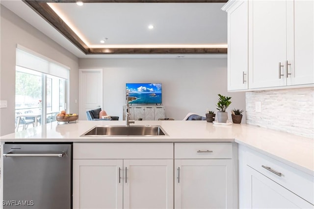 kitchen featuring white cabinets, dishwasher, sink, kitchen peninsula, and a tray ceiling