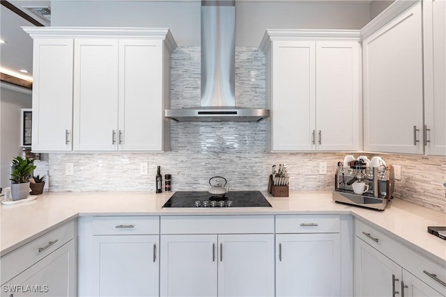 kitchen with white cabinetry, backsplash, wall chimney range hood, and black electric cooktop