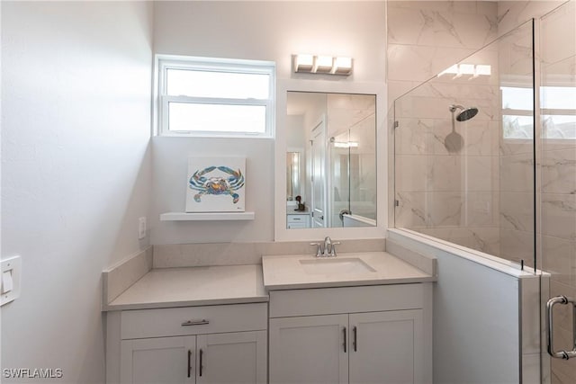 bathroom with a wealth of natural light, a shower with shower door, and vanity