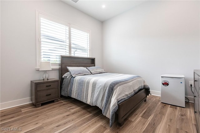 bedroom featuring refrigerator and hardwood / wood-style floors