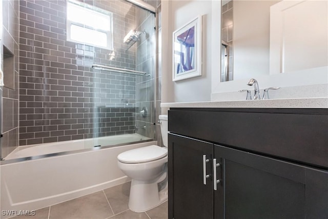 full bathroom with bath / shower combo with glass door, tile patterned floors, vanity, and toilet