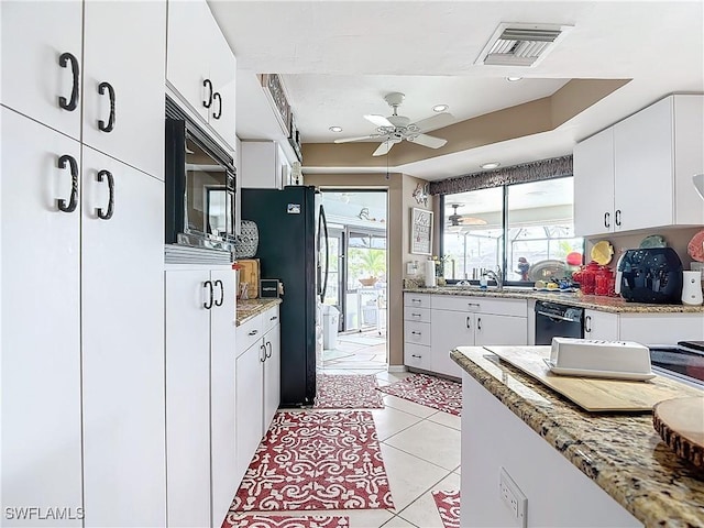 kitchen with light tile patterned floors, a wealth of natural light, white cabinets, and black appliances