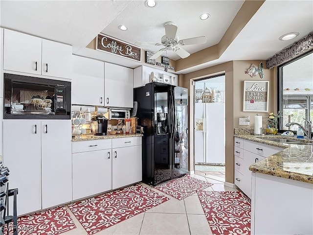 kitchen featuring light tile patterned flooring, light stone countertops, black appliances, white cabinets, and sink