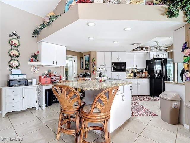 kitchen with ceiling fan, a center island, black appliances, light tile patterned flooring, and white cabinets