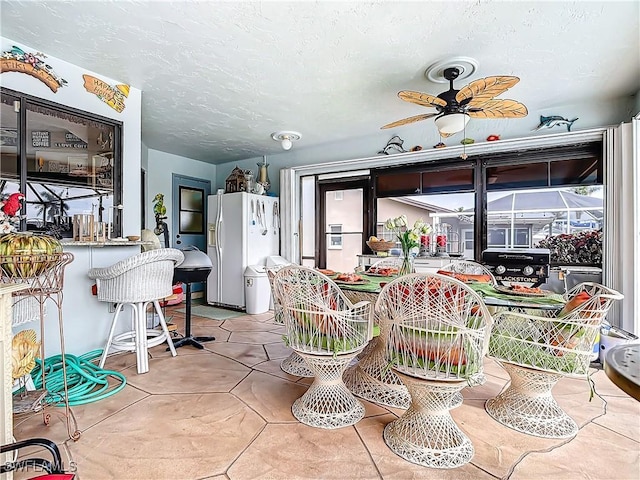 tiled dining space featuring a textured ceiling and ceiling fan