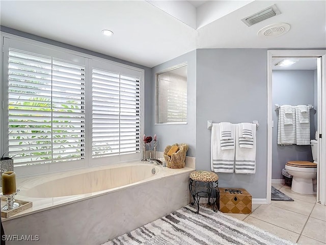 bathroom with a washtub, toilet, and tile patterned flooring