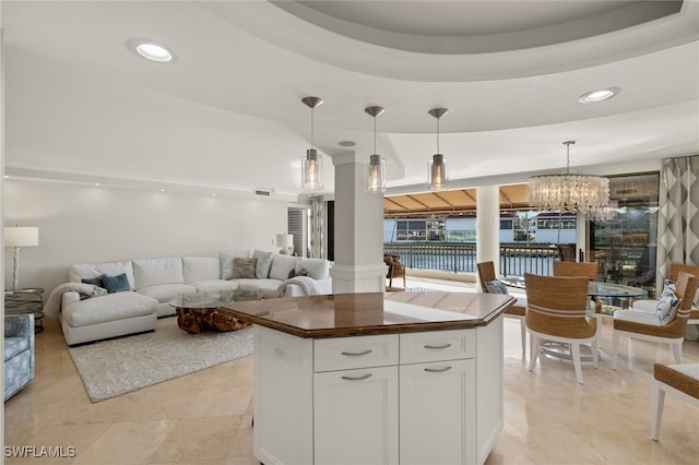 kitchen with white cabinets, a kitchen island, a tray ceiling, and pendant lighting