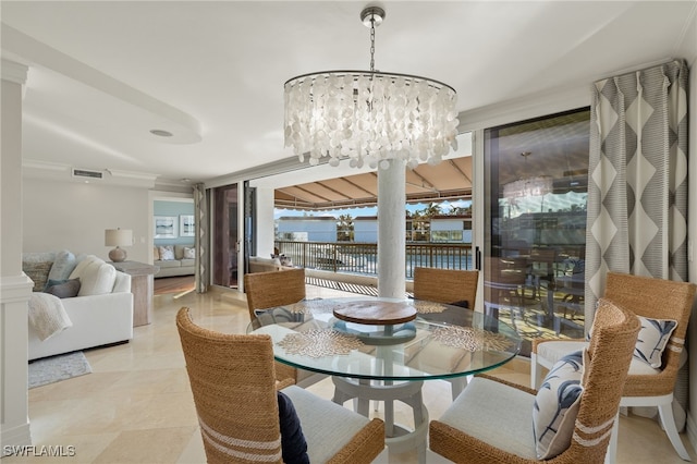 dining room with an inviting chandelier, ornate columns, crown molding, a water view, and expansive windows