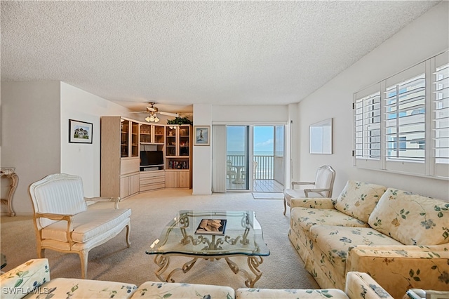 living room with light carpet, ceiling fan, and a textured ceiling