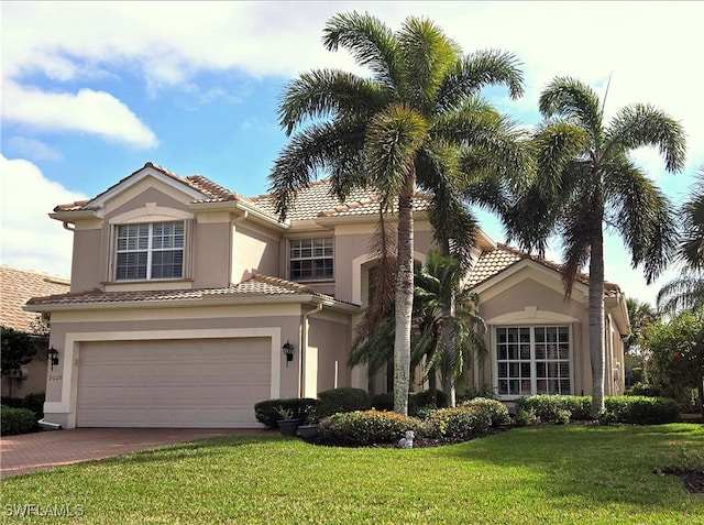 mediterranean / spanish-style house with a garage, stucco siding, a tiled roof, and a front lawn