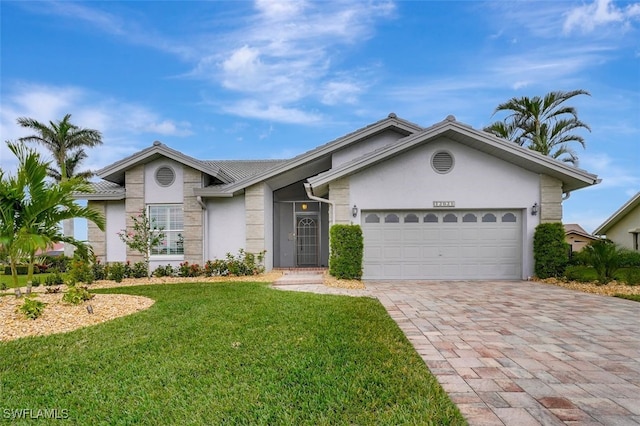 view of front of home featuring a front lawn, decorative driveway, a garage, and stucco siding