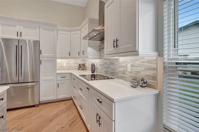 kitchen with white cabinetry, wall chimney exhaust hood, black electric cooktop, and high end fridge