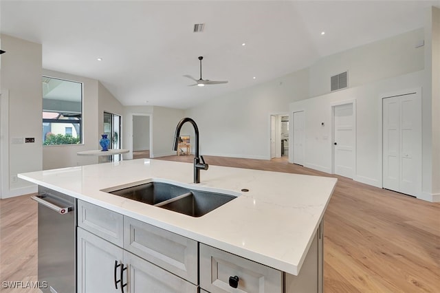 kitchen with light hardwood / wood-style floors, a center island with sink, ceiling fan, light stone countertops, and sink