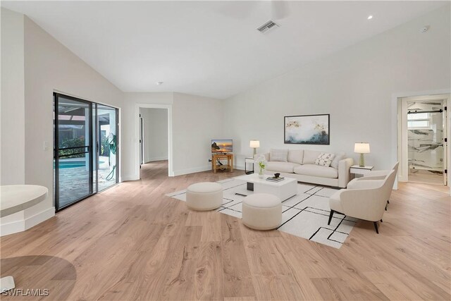 living room with high vaulted ceiling and light hardwood / wood-style flooring