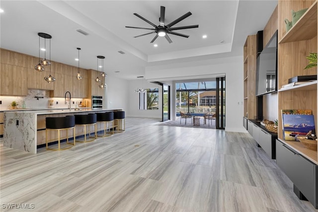 living room with a tray ceiling and ceiling fan