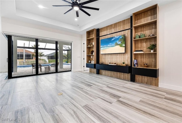 unfurnished living room with a raised ceiling and ceiling fan