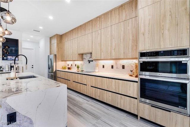 kitchen featuring sink, decorative light fixtures, light brown cabinets, and appliances with stainless steel finishes