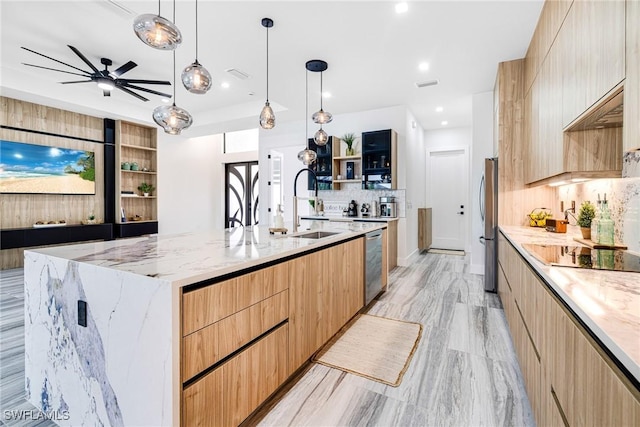 kitchen featuring light stone counters, decorative light fixtures, a spacious island, and appliances with stainless steel finishes