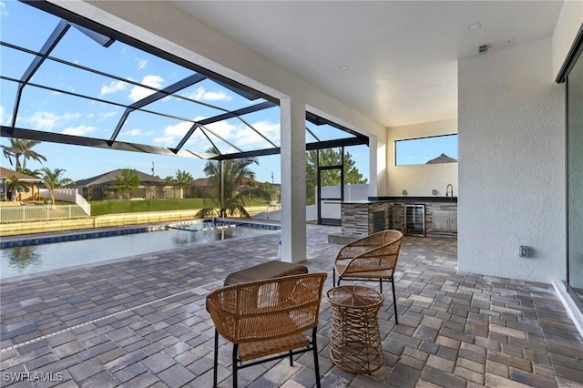 view of patio with a bar, an outdoor kitchen, beverage cooler, pool water feature, and a lanai