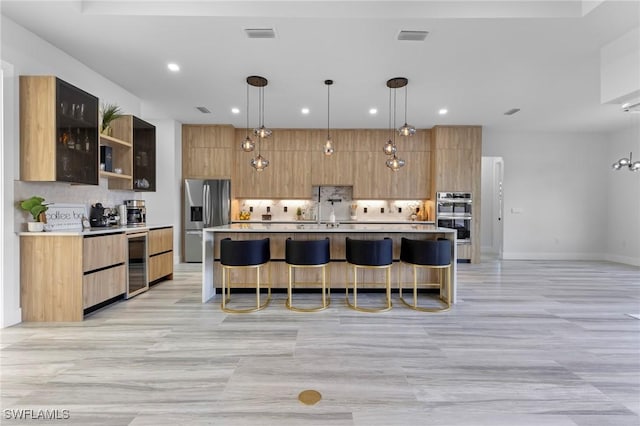 kitchen with hanging light fixtures, appliances with stainless steel finishes, a large island, and decorative backsplash