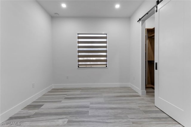 unfurnished bedroom with light tile patterned floors and a barn door