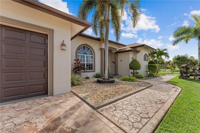 view of exterior entry featuring a lawn and a garage