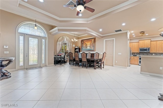 tiled dining area featuring ceiling fan with notable chandelier, a tray ceiling, and ornamental molding