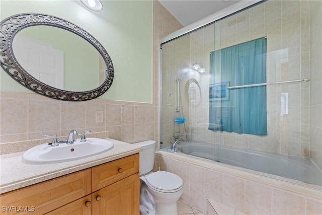 full bathroom with bath / shower combo with glass door, toilet, vanity, and tile walls