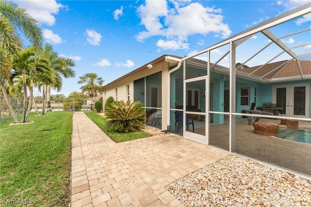 back of house with a lanai, a lawn, french doors, and a patio