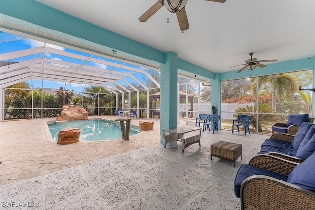 view of pool with ceiling fan, glass enclosure, a patio area, and an outdoor living space