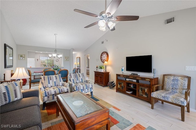 living room featuring vaulted ceiling, ceiling fan with notable chandelier, and light hardwood / wood-style floors