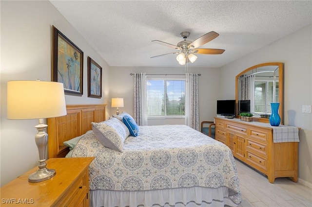 bedroom with ceiling fan, a textured ceiling, and light hardwood / wood-style flooring