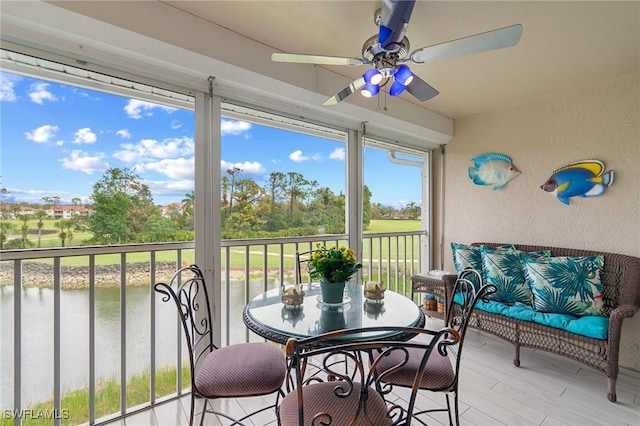 sunroom featuring ceiling fan and a water view