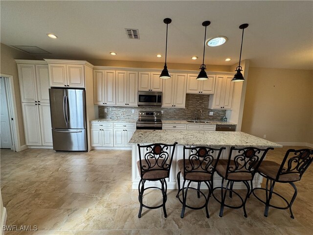 kitchen with sink, a kitchen bar, a center island, stainless steel appliances, and light stone countertops