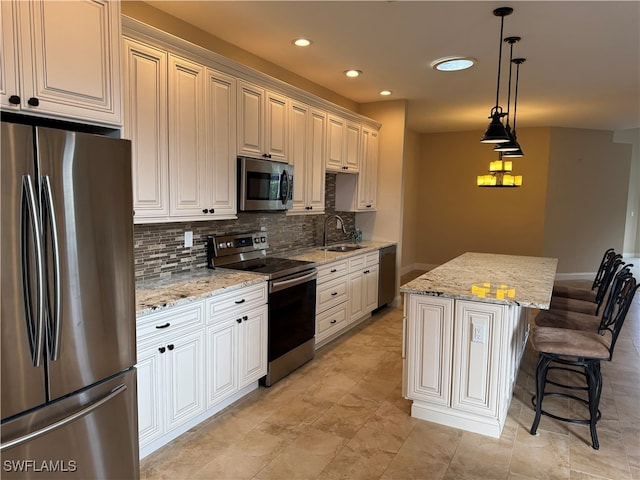 kitchen featuring light stone countertops, appliances with stainless steel finishes, a center island, and sink