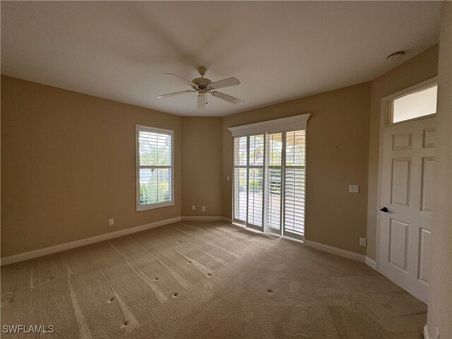 carpeted spare room featuring ceiling fan and a healthy amount of sunlight